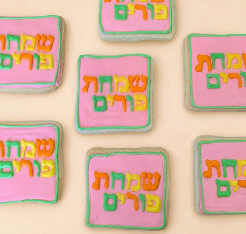 Pink Purim cookies with rainbow lettering
